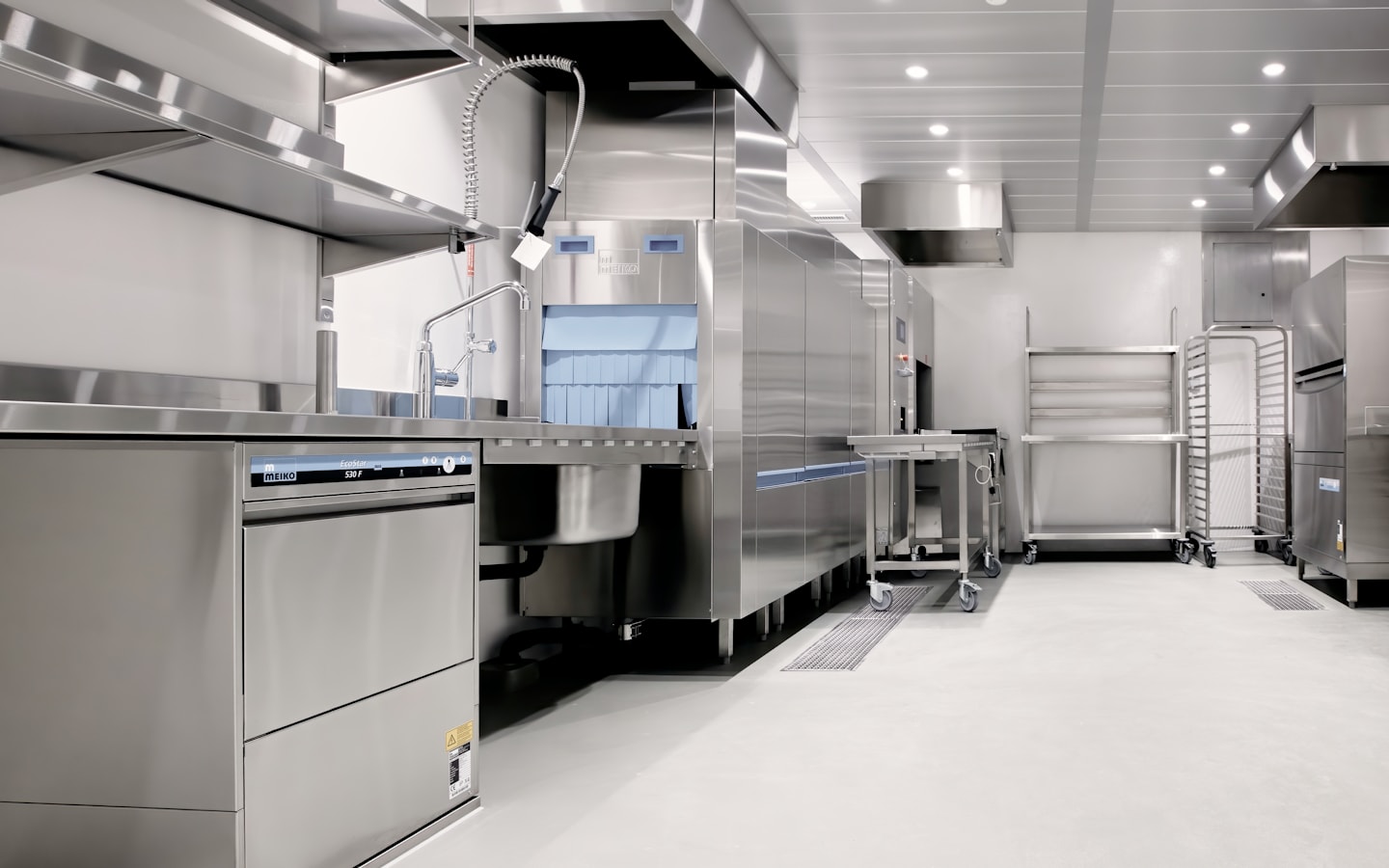 A professional commercial kitchen with a stainless steel washing station and shelving