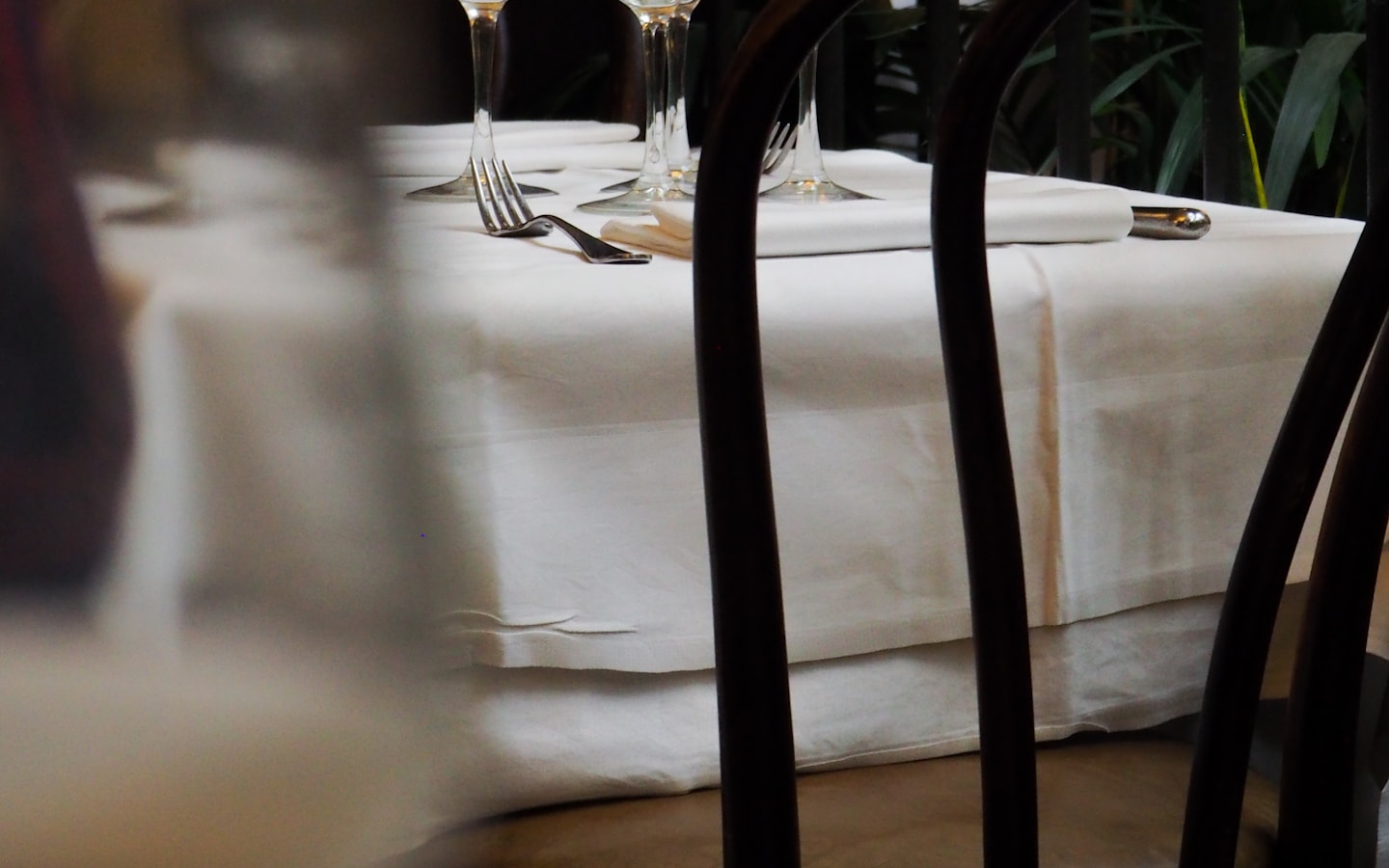 A restaurant table laid with glassware, cutlery and place settings
