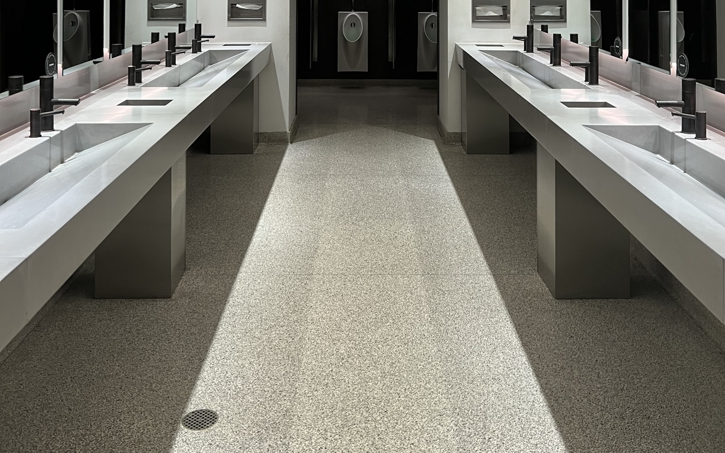 A commercial washroom with a run of basins beneath a continuous mirror wall